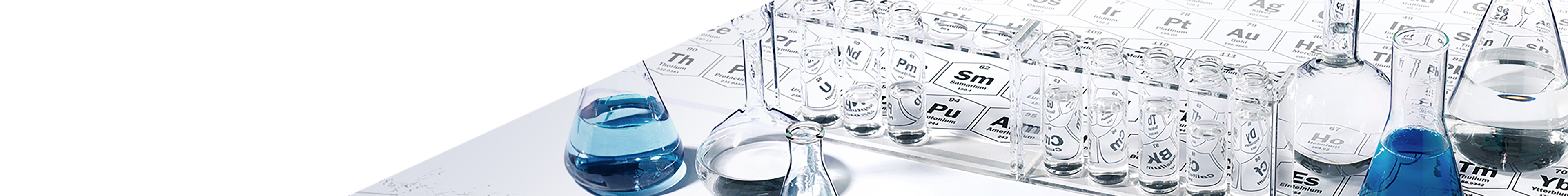 Scientific glassware including beakers and flasks filled with clear and blue liquids placed on a periodic table, representing dermatological science and precise formulation.